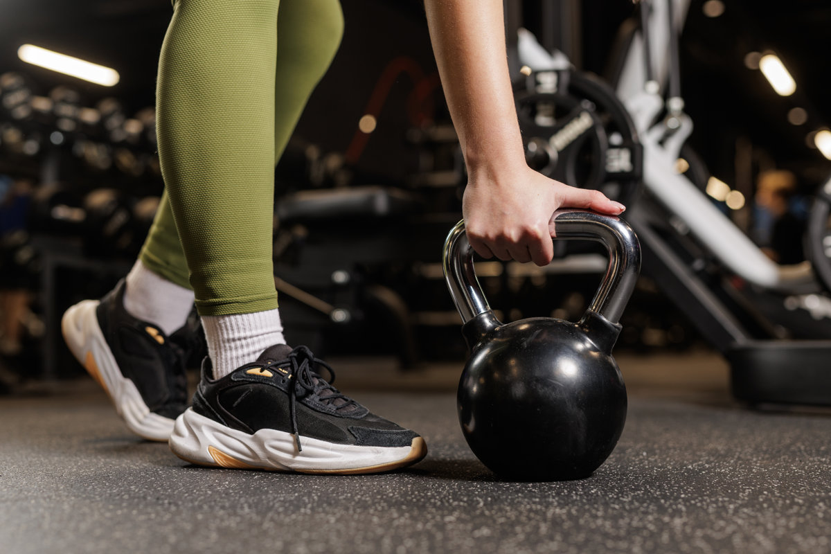 Closeup of woman hand holding kettlebell on gym floor for functional strength training workout